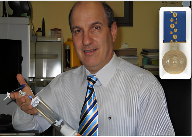 Safer Infusion Systems, Inc. Man holding device, blue-striped tie, medal displayed.